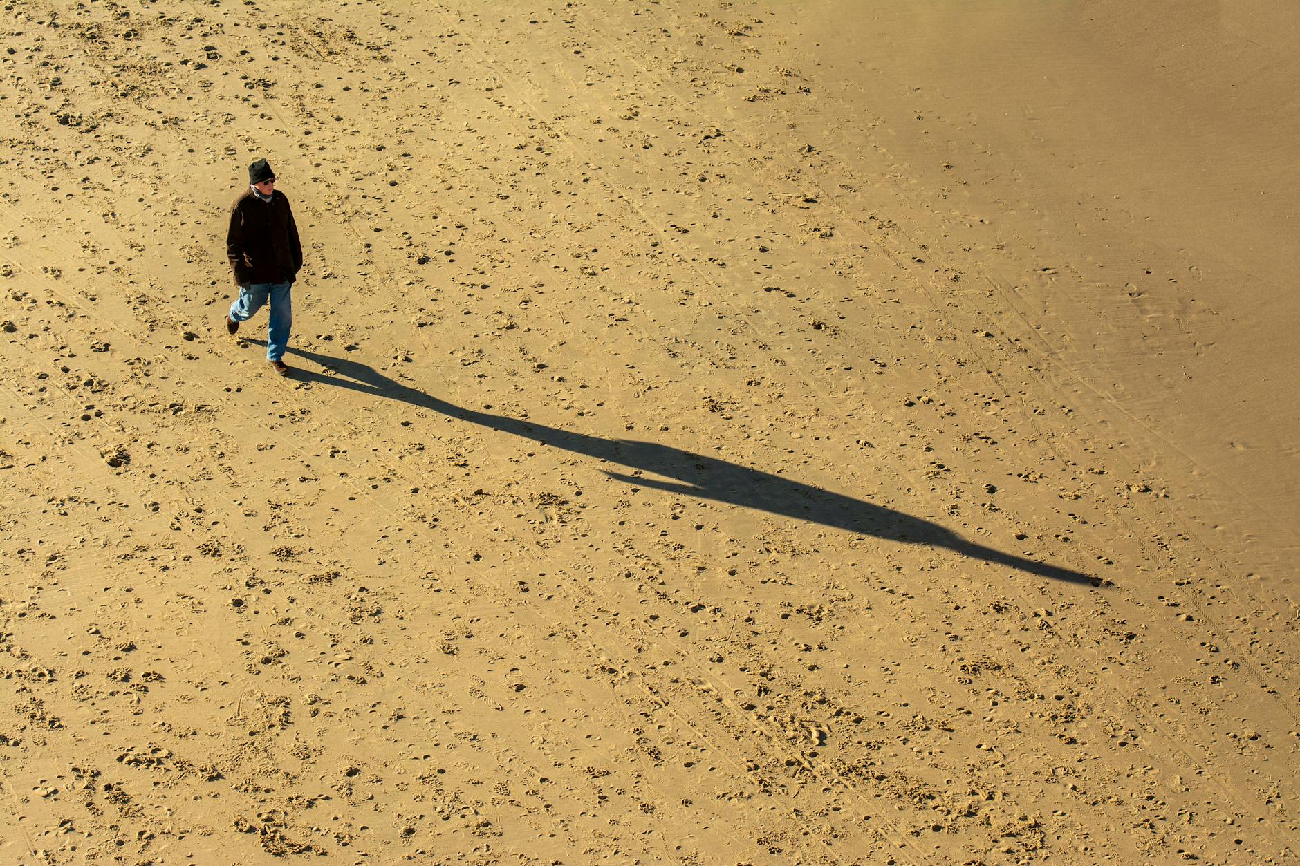 person casting shadow on sandy beach